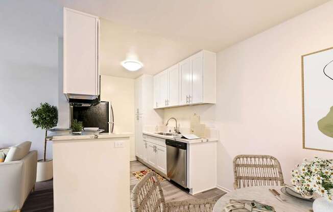 A modern kitchen with white cabinets and appliances, a dining table with chairs, and a potted plant.