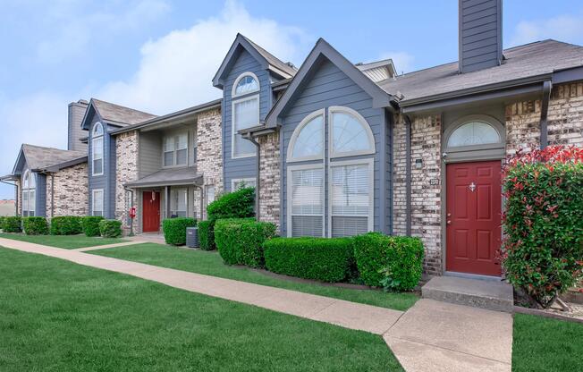 a large brick building with grass in front of a house
