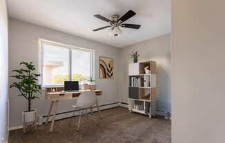 an office with a ceiling fan and a desk with a laptop