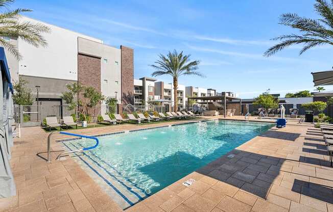 A swimming pool surrounded by lounge chairs and palm trees.