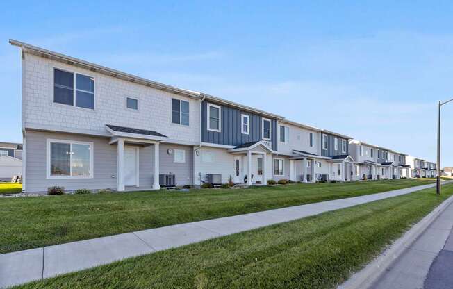 A row of houses with a sidewalk in front.