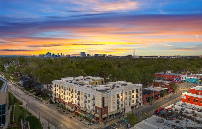 Aerial view of West 39th Apartments and surrounding Kansas City neighborhood with skyline in background at sunset.
