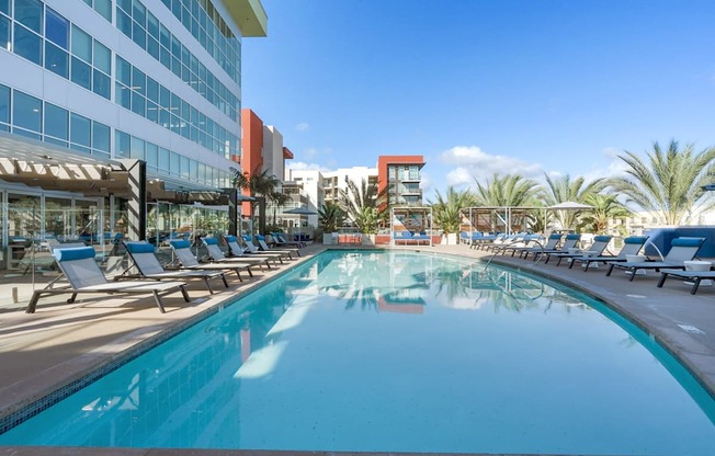 A large swimming pool with lounge chairs and a building in the background.