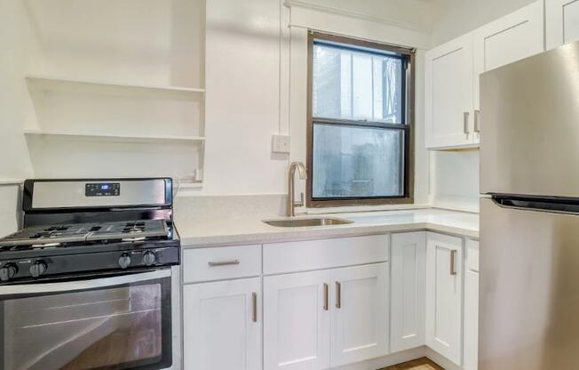 A modern kitchen with a stove, sink, and refrigerator.