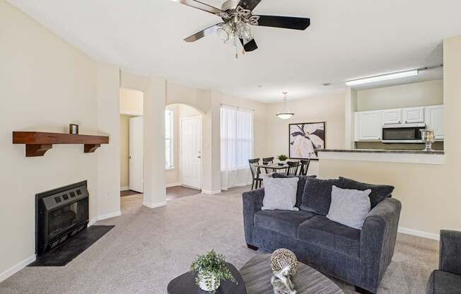 A living room with a grey couch, a black fireplace, and a ceiling fan.