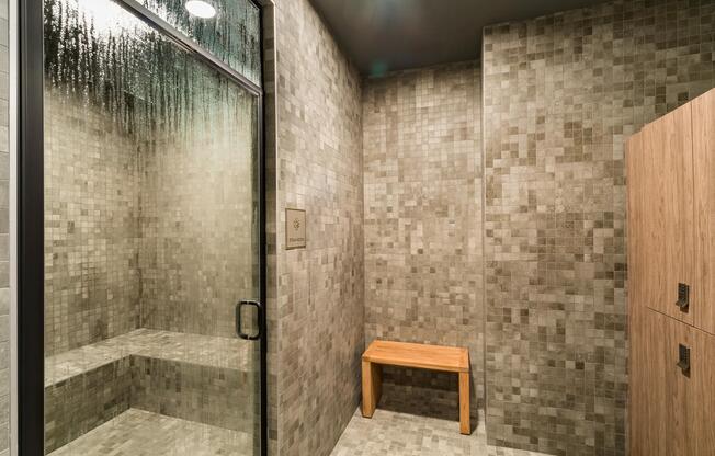 A calming steam room with tiled walls and warm finishes, creating a quiet space to decompress and recharge after the day.
