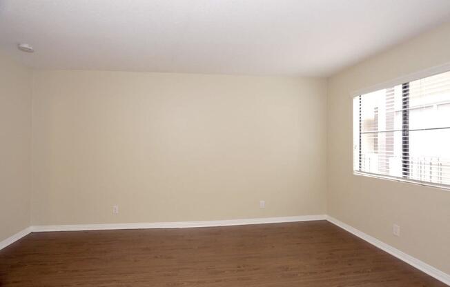 an empty living room with wood floors and a large window