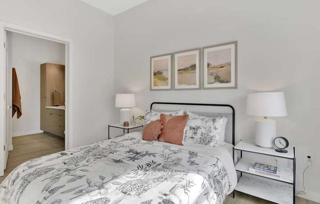 A bedroom with a large bed and a nightstand with a lamp on it.