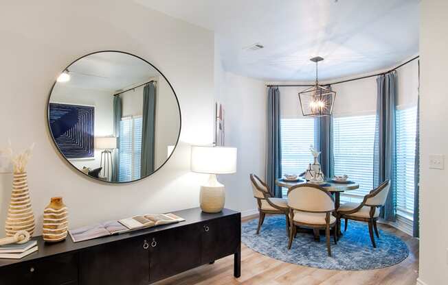 a dining area with a table and chairs and a large mirror