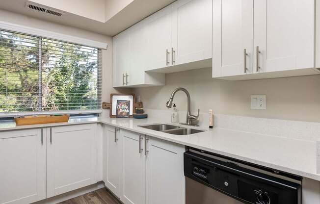 a kitchen with white cabinets and a sink and a window