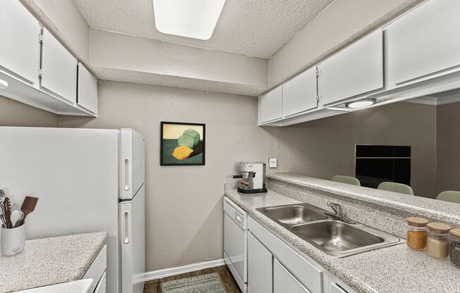 a kitchen with white cabinets and a sink and a refrigerator