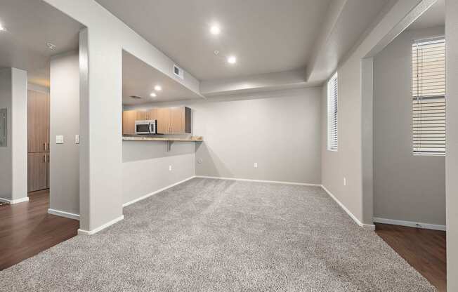 A spacious room with a carpeted floor and a kitchenette in the corner.