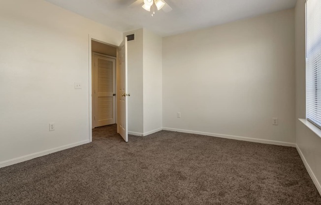 an empty bedroom with carpet and a door to a closet