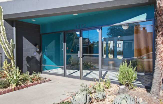 the front of a building with glass doors and a sidewalk