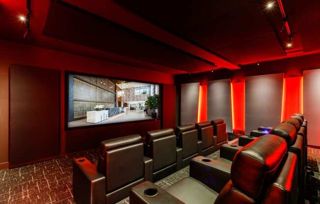 a home theater room with leather seats and a large screen at One Ten Apartments, Jersey City , NJ