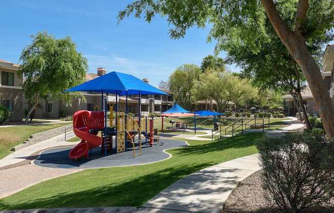 A playground with a red slide and a blue canopy.