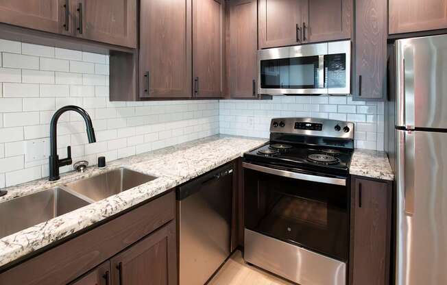 A kitchen with a stove, sink, and refrigerator.