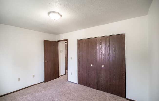 Bismarck, ND Rosser Apartments. a bedroom with two doors and a carpeted floor