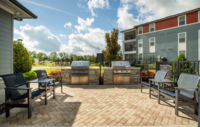 a patio with two barbecue grills and chairs on it