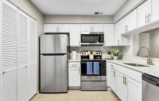 a kitchen with stainless steel appliances and white cabinets at Reserve at Temple Terrace, Temple Terrace