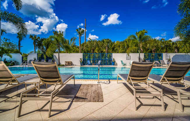 a swimming pool with chairs and a blue sky at Magnolia Square, Naples, 34109