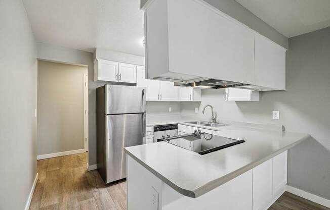 A kitchen with white cabinets and a stainless steel refrigerator.
