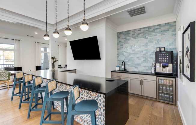 a kitchen with a long bar with blue chairs