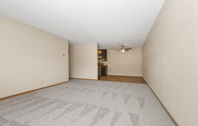 Anoka, MN Dellwood Estates Apartments. An empty living room with a ceiling fan and a kitchen in the background