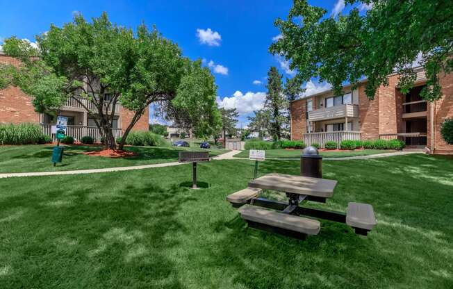 a picnic table in the grass outside of an apartment building