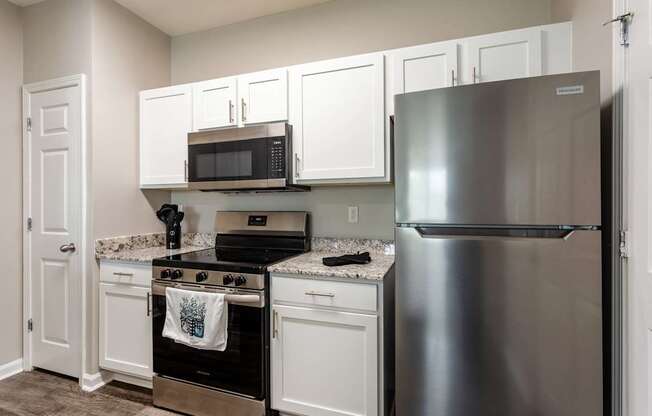 A kitchen with a stainless steel refrigerator, microwave, and oven.