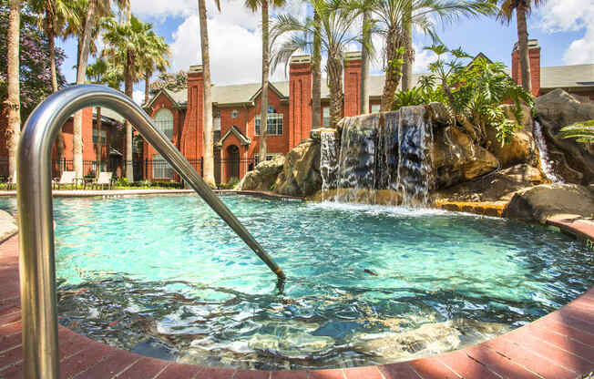 a pool with a waterfall in front of a house