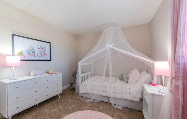 A baby's room with a white crib and a white dresser with a pink blanket on top.