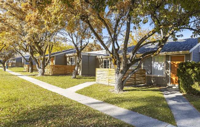 Sidewalks outside units with fenced yards with large trees and grassy areas at Park View Apartments, Washington