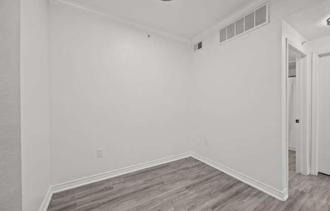 an empty room with white walls and wood flooring