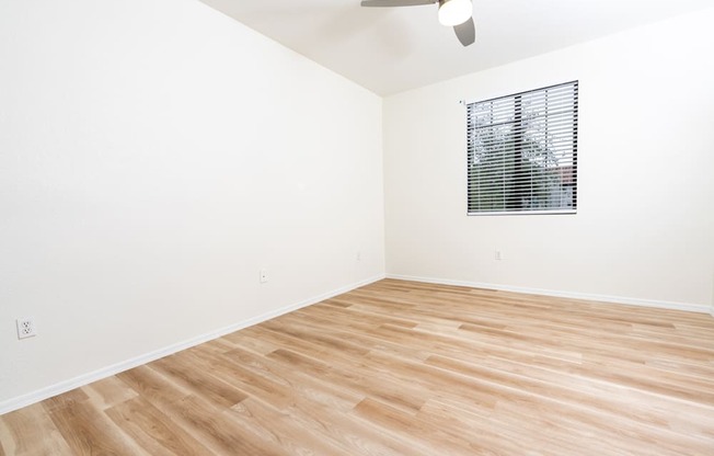 an empty room with wood flooring and a window