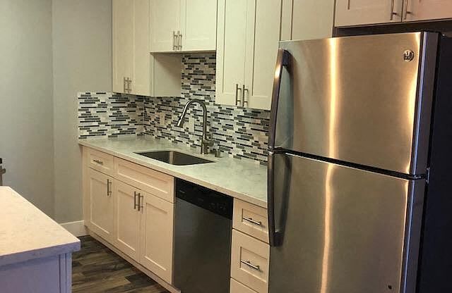 A kitchen with a stainless steel refrigerator and white cabinets.