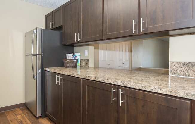 a kitchen with wooden cabinets and a granite counter top and a refrigerator