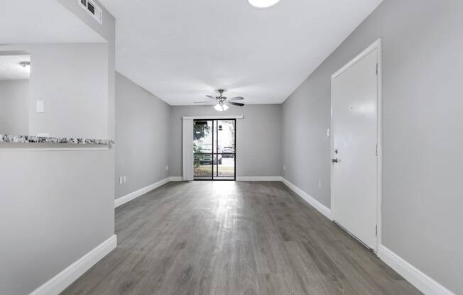 an empty living room with white walls and a ceiling fan