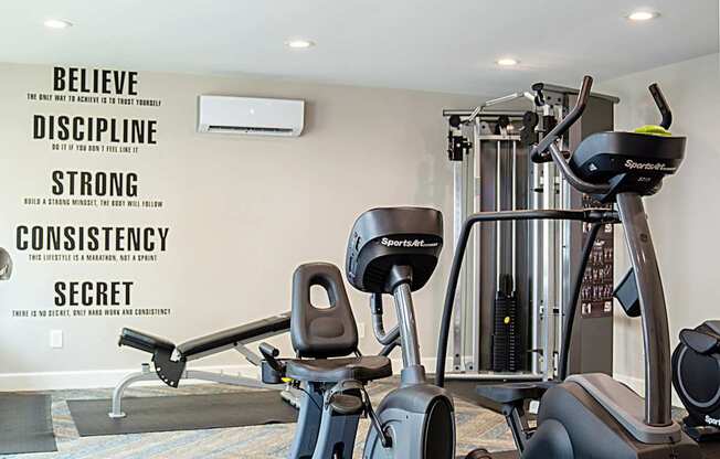 A gym with a wall that has the words Believe, Discipline, Strong, Consistency, and Secret written on it.