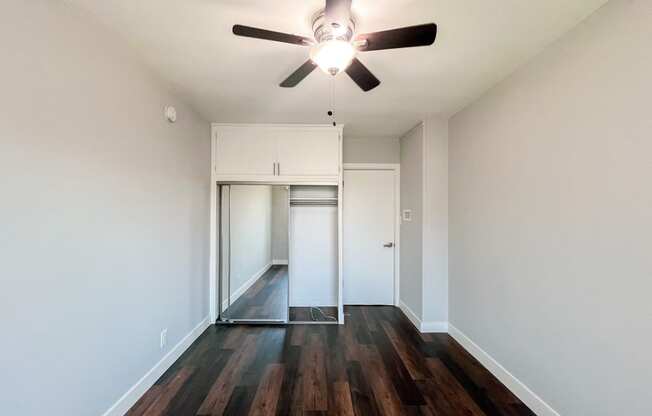 an empty living room with hardwood floors and a ceiling fan