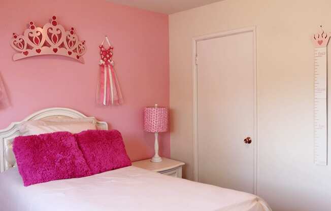 a pink bedroom with a white bed and a princess tiara