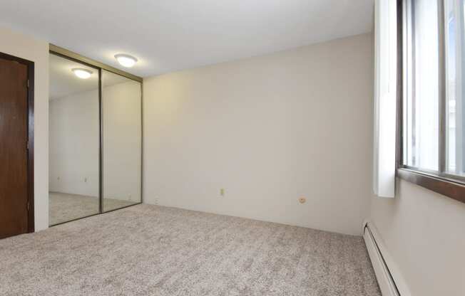 a bedroom with a large mirror and a carpeted floor. Roseville, MN Rosedale Estates