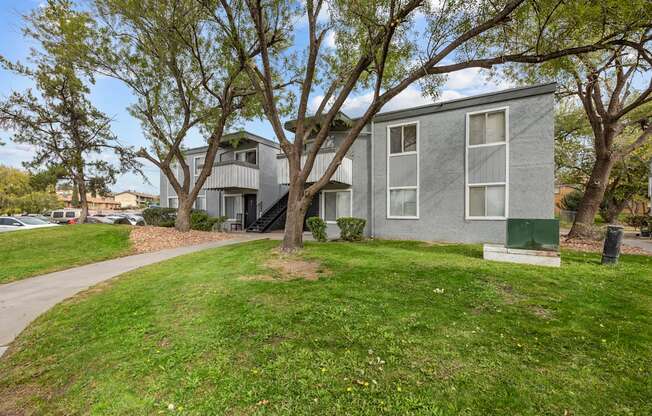 A grey building with a green post box in front.