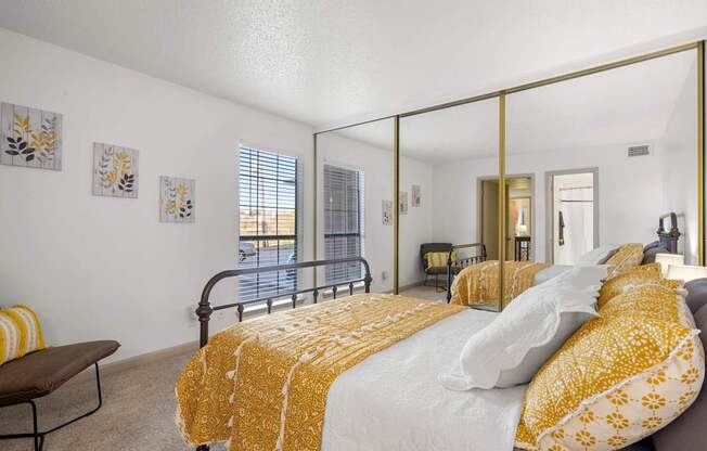 A bedroom with a bed covered in a yellow and white comforter.
