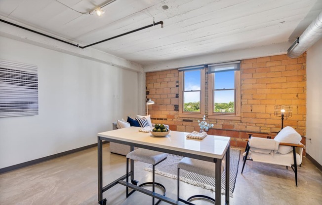 a dining room with a table and chairs and a brick wall