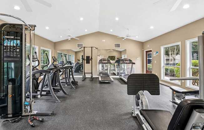A spacious gym with a variety of equipment including treadmills, elliptical machines, and a weight machine.