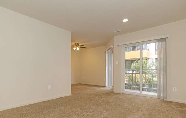 an empty living room with a window and a ceiling fan