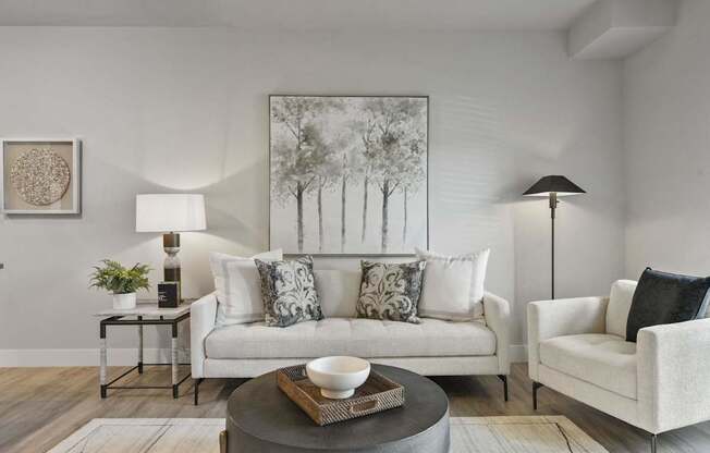 A living room with a white couch, a grey coffee table, and a painting on the wall.