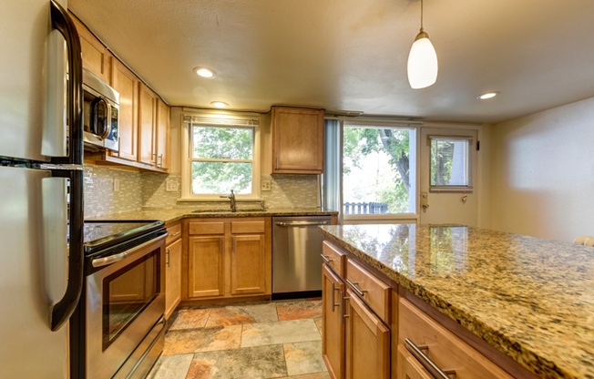 an updated kitchen with granite counter tops and wooden cabinets