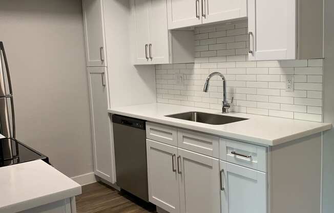 an empty kitchen with white cabinets and a sink